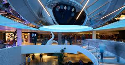 An evening scene of stairs and guests aboard Virgin Voyages's Scarlet Lady Cruise Ship. 